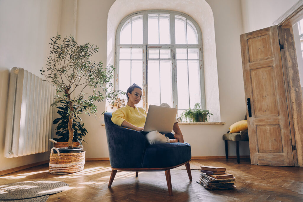 beautiful-young-woman-using-laptop-while-sitting-comfortable-chair-home
